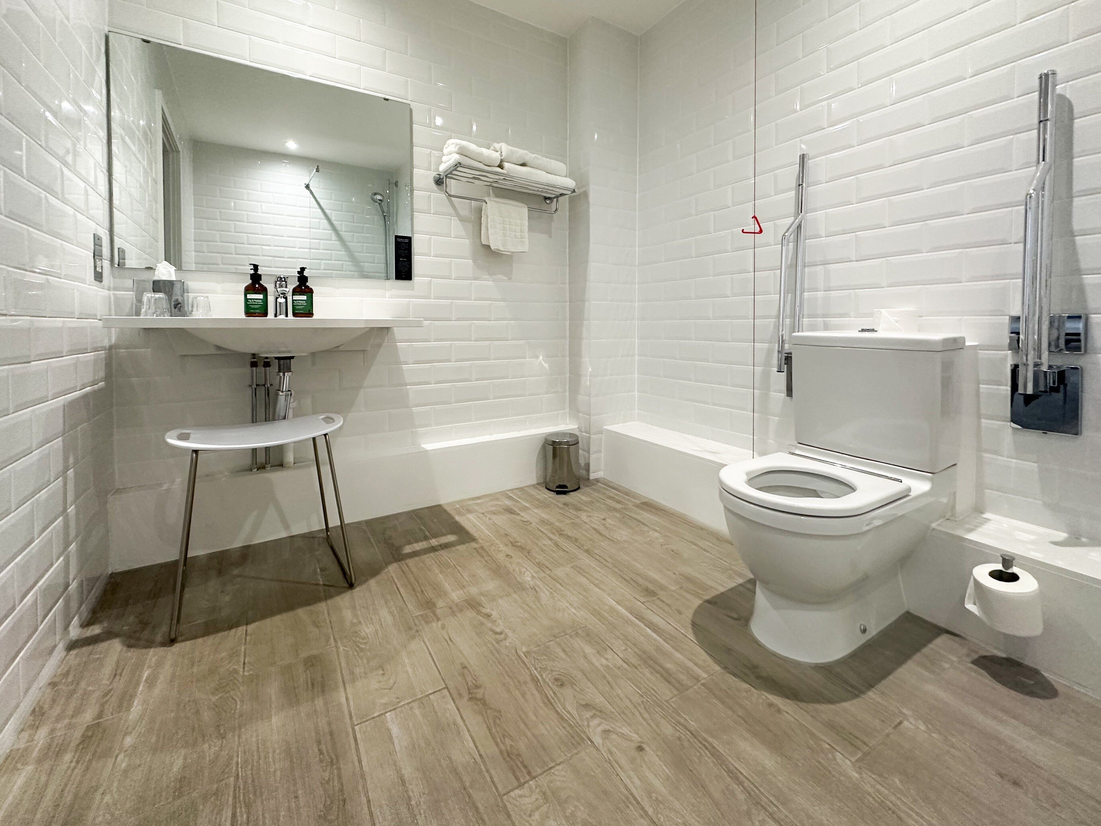 Un baño moderno con lavamanos, espejo e inodoro blancos.