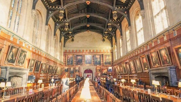 A long, narrow hall with wooden benches and tables, high ceilings with intricate woodwork, and large windows. - voco Oxford Spires by IHG (Oxford)