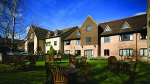 A courtyard with outdoor seating and a brick building with multiple windows. - voco Oxford Spires by IHG (Oxford)