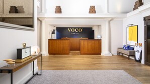 A reception area with a wooden reception desk, a clock, and a sofa with umbrellas.
