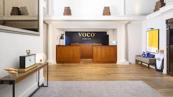 A reception area with a wooden reception desk, a clock, and a sofa with umbrellas.
