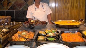 A buffet with various dishes including seafood, vegetables, and a large pot of rice. - Pine Lake Inn (Mbombela)