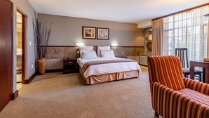 A hotel room with a large bed, a chair, a nightstand, a vase, and a window with curtains. - Pine Lake Inn (Mbombela)