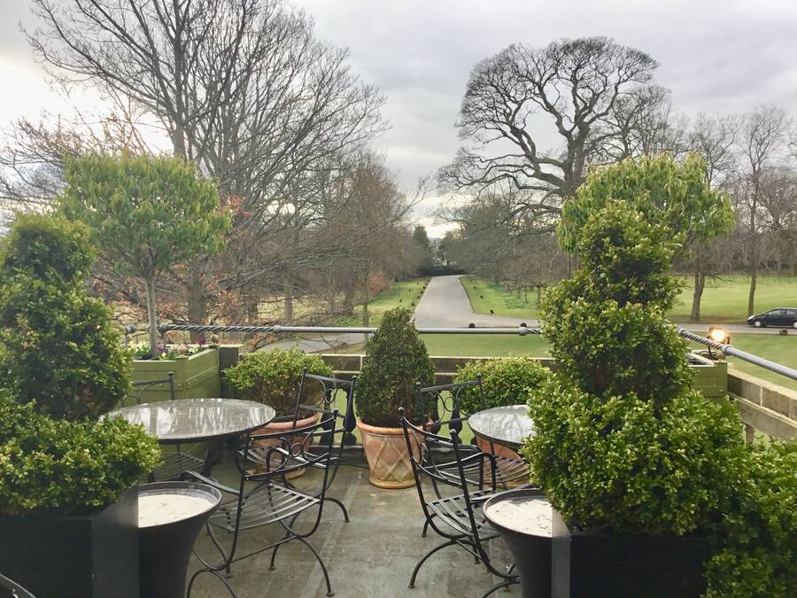 A patio area with outdoor seating and a view of a park.