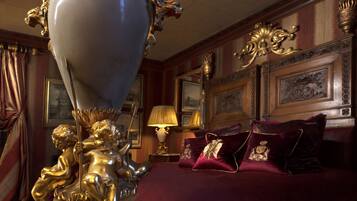A luxurious bedroom with a large bed, ornate gold fixtures, and framed artwork on the walls.