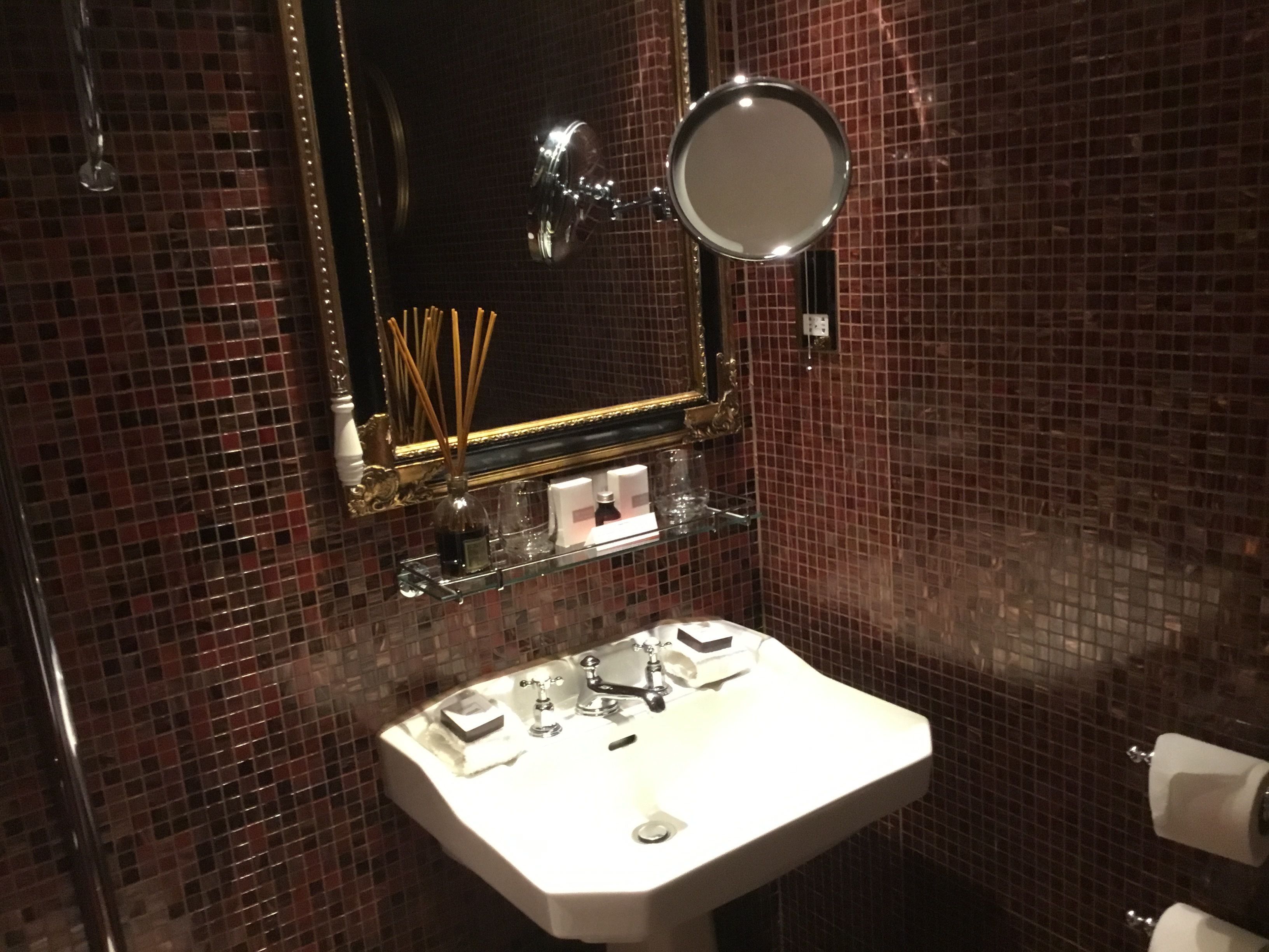 A bathroom with a white sink, a mirror, and a small shelf with toiletries.