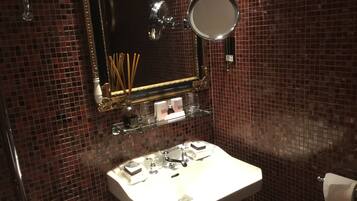 A bathroom with a white sink, a mirror, and a small shelf with toiletries.