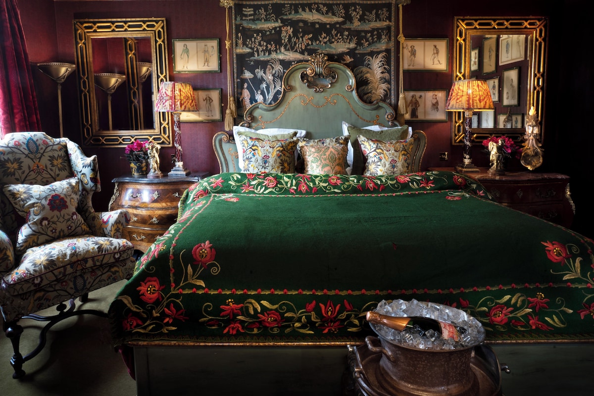 A traditional room with a large bed, ornate furniture, and a tapestry on the wall.