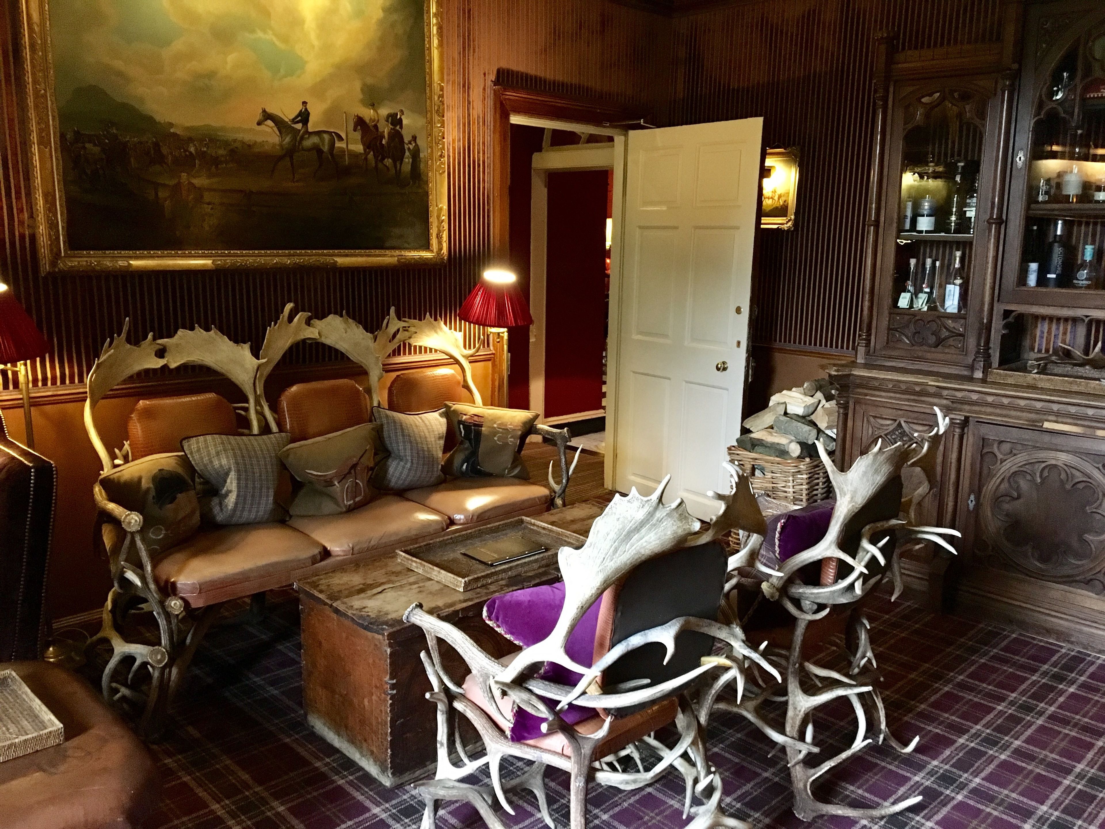 A room with a sofa set, a painting, a door, and antler decorations.