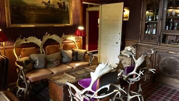 A room with a sofa set, a painting, a door, and antler decorations.