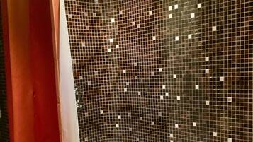 A bathroom with a bathtub, a shower curtain, and a tiled wall.