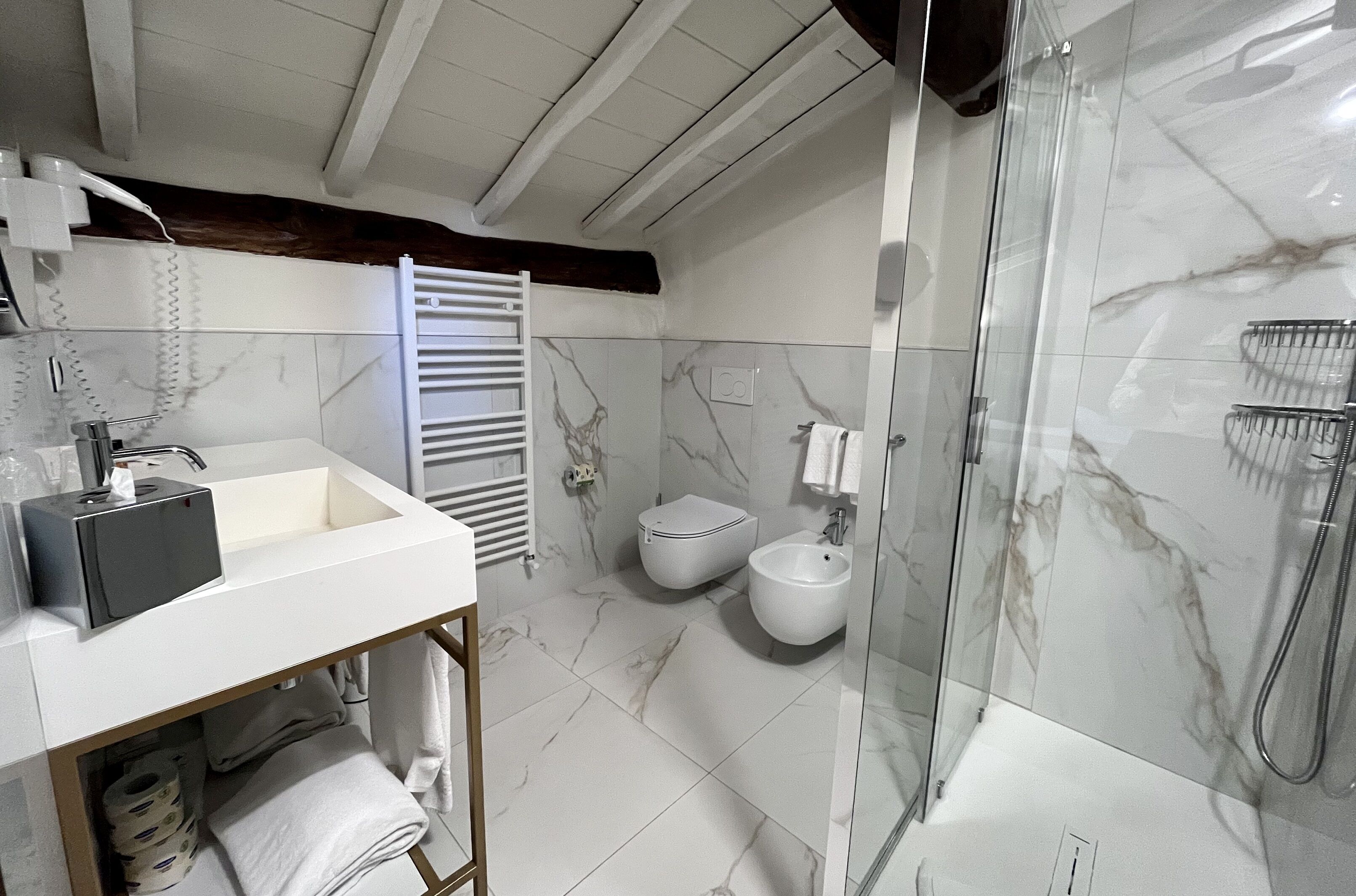 Une salle de bain moderne avec un lavabo blanc, des toilettes, un bidet et une douche à parois de verre.