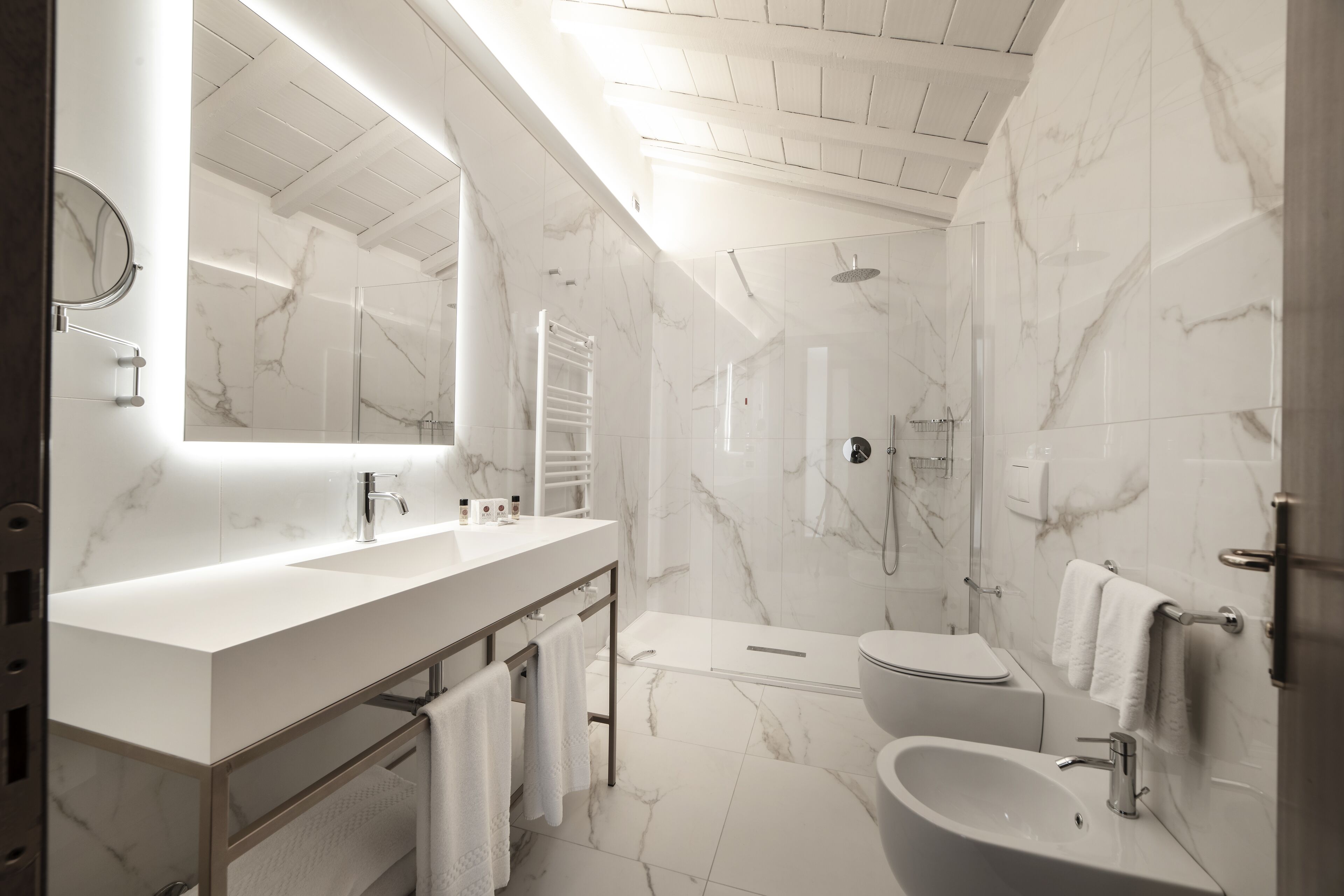 A modern bathroom with a marble vanity, a freestanding bathtub, and a separate toilet.
