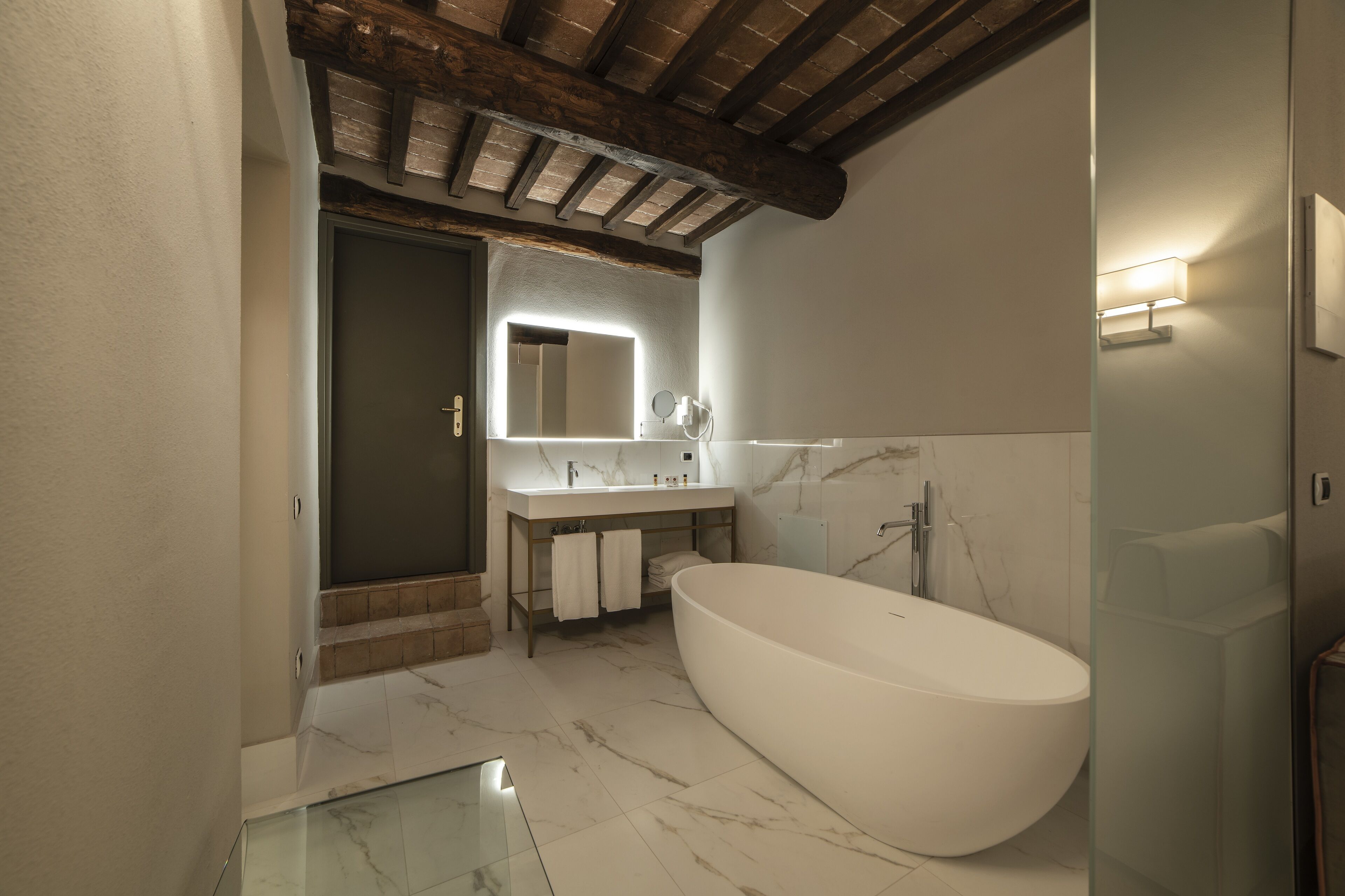 A modern bathroom with a freestanding bathtub, a vanity with a mirror, and a shower area.