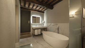 A modern bathroom with a freestanding bathtub, a vanity with a mirror, and a shower area.