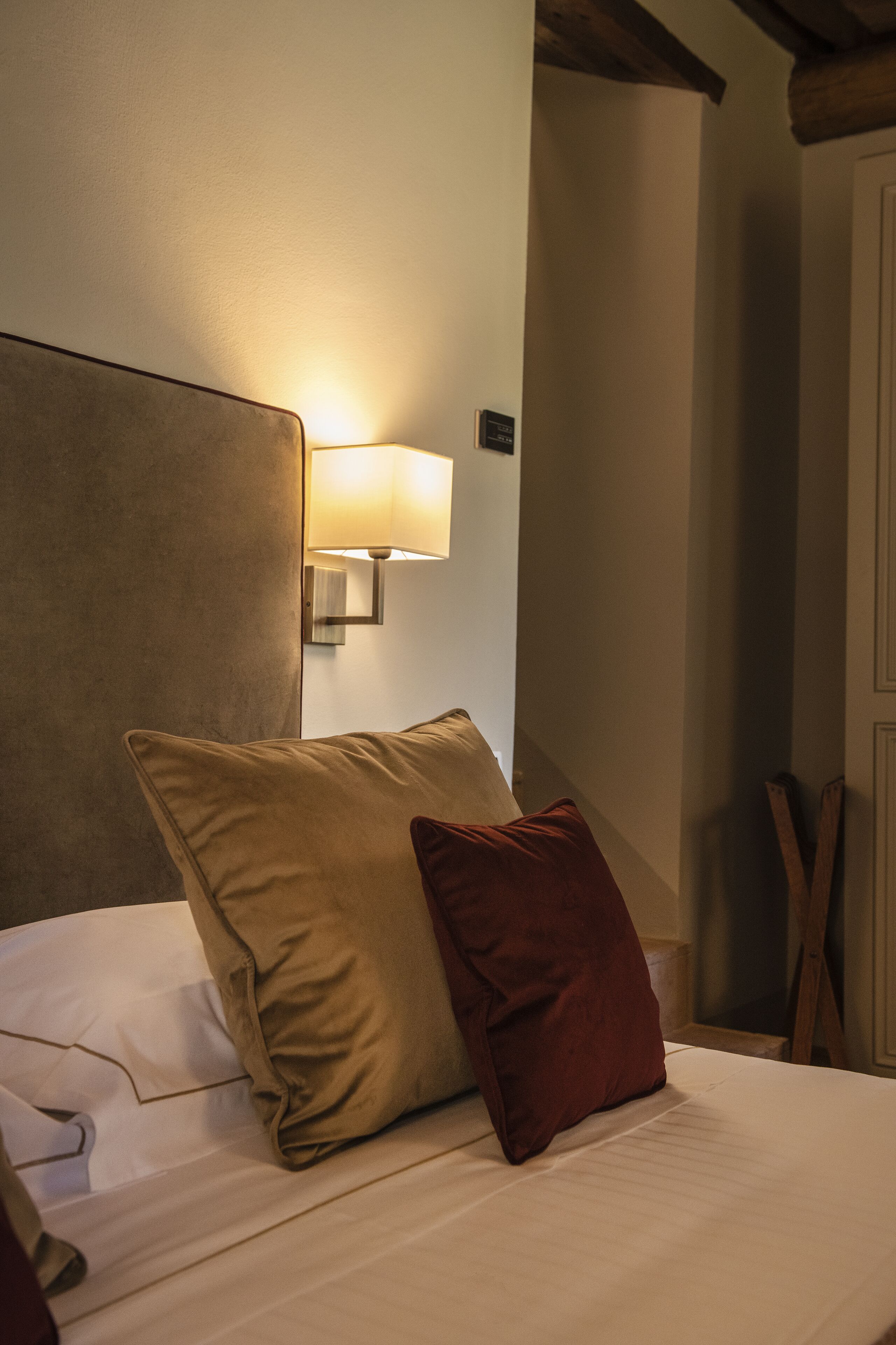 Una habitación de hotel con una cama, una lámpara de pared y un cabecero de madera.