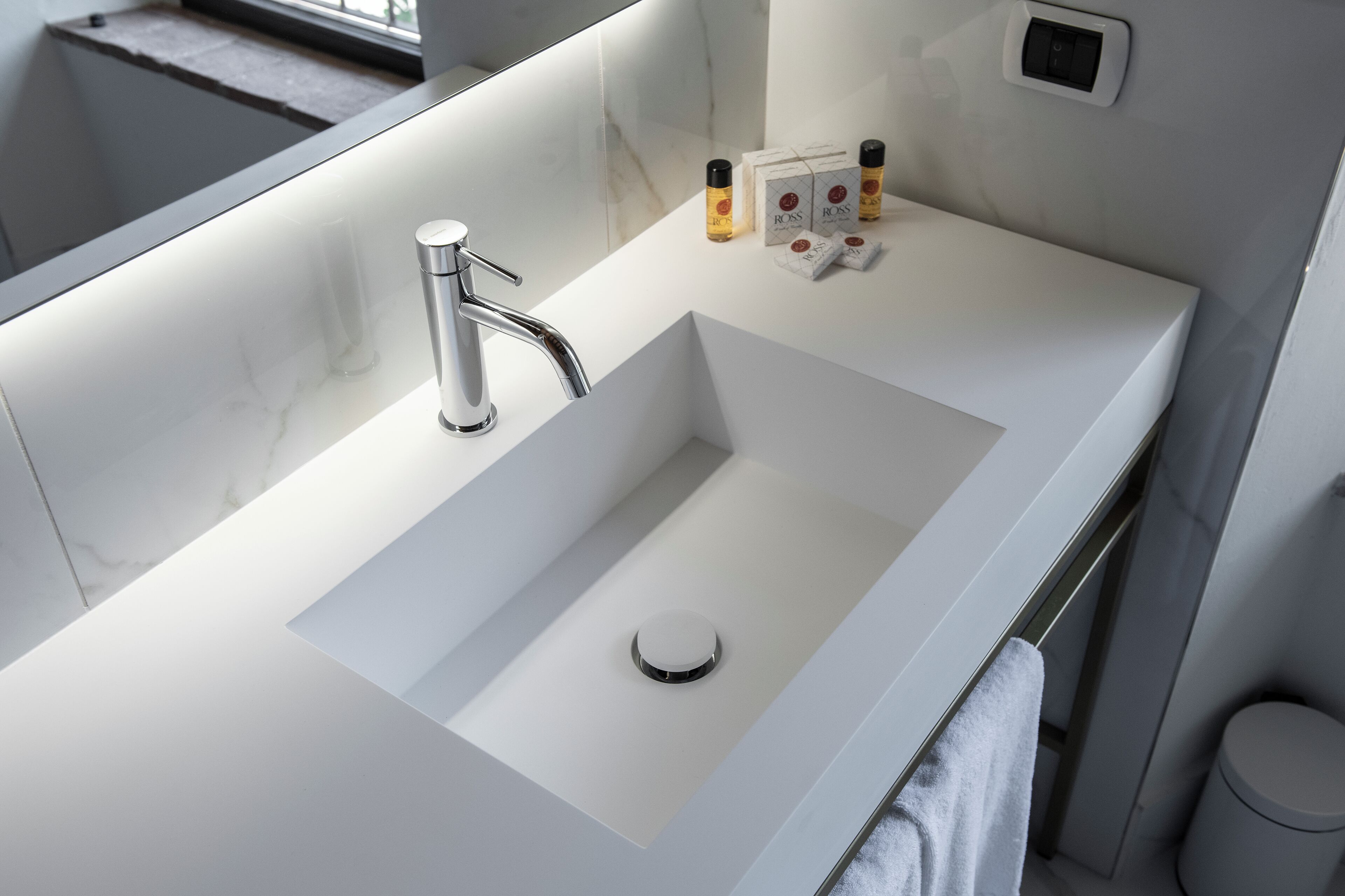 A modern bathroom with a white sink, chrome faucet, and a mirror above it.