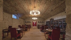 A spacious room with a high ceiling, wooden beams, and a chandelier. There are tables and chairs arranged for dining, and a wine rack filled with bottles. - Relais Della Rovere (Colle di Val d'Elsa)