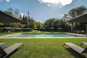 Una piscina al aire libre, sombrillas, sillones reclinables de piscina