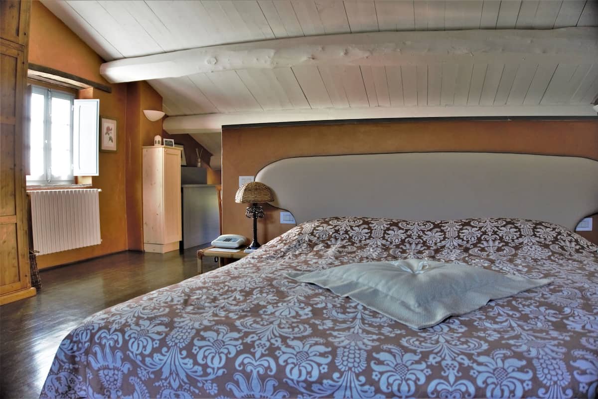 Une chambre avec un grand lit, un plafond en bois et un radiateur.