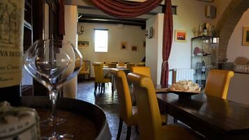 Ein Restaurantinneres mit gelben Stühlen, einem Tisch mit einem Teller Essen und einem Weinglas.