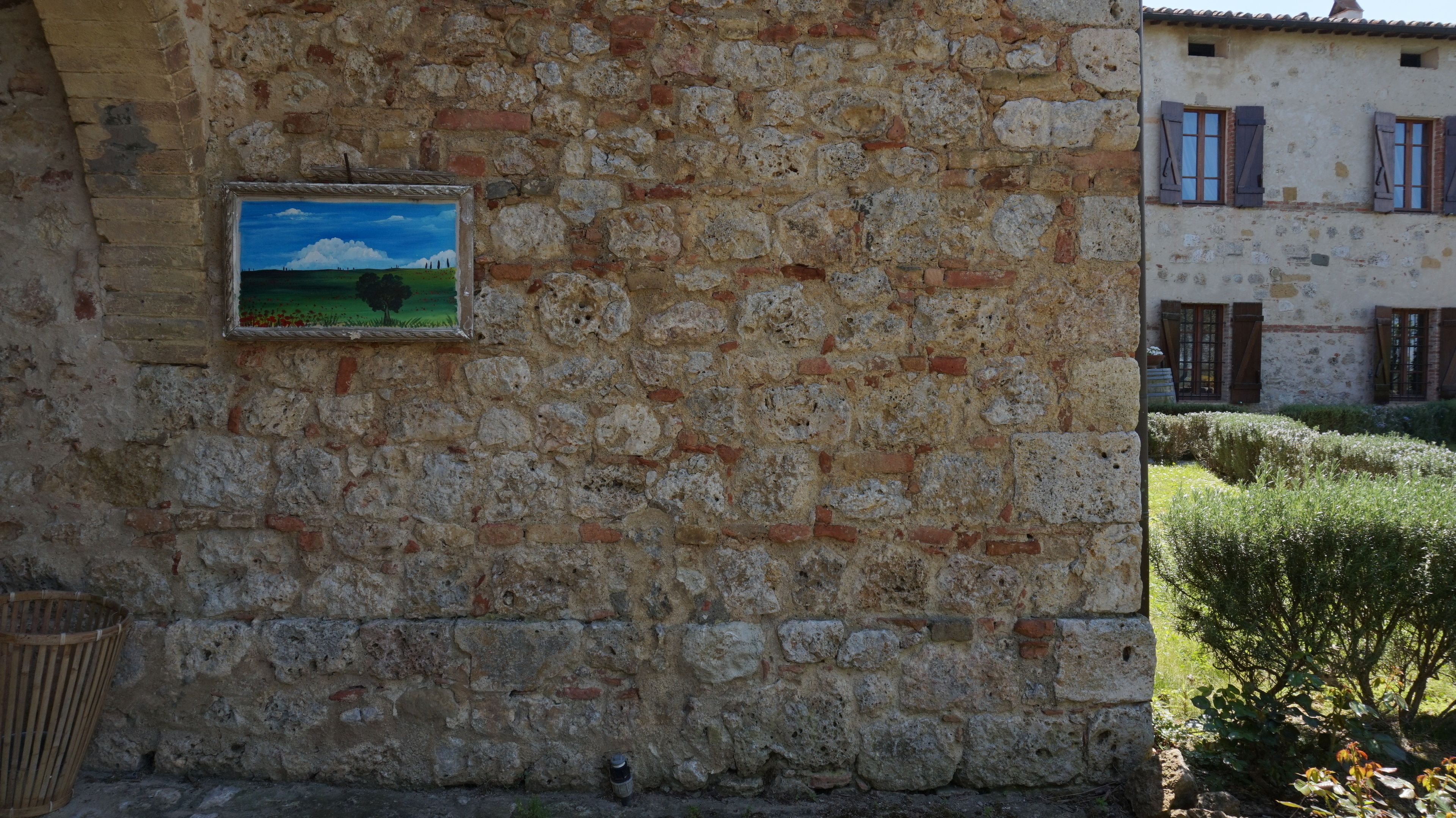 A stone building with a rustic appearance, featuring a framed painting of a landscape.