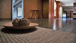 A room with a woven basket on a round table, a wooden chair, and a wooden floor. - Relais Castel Bigozzi (Monteriggioni)