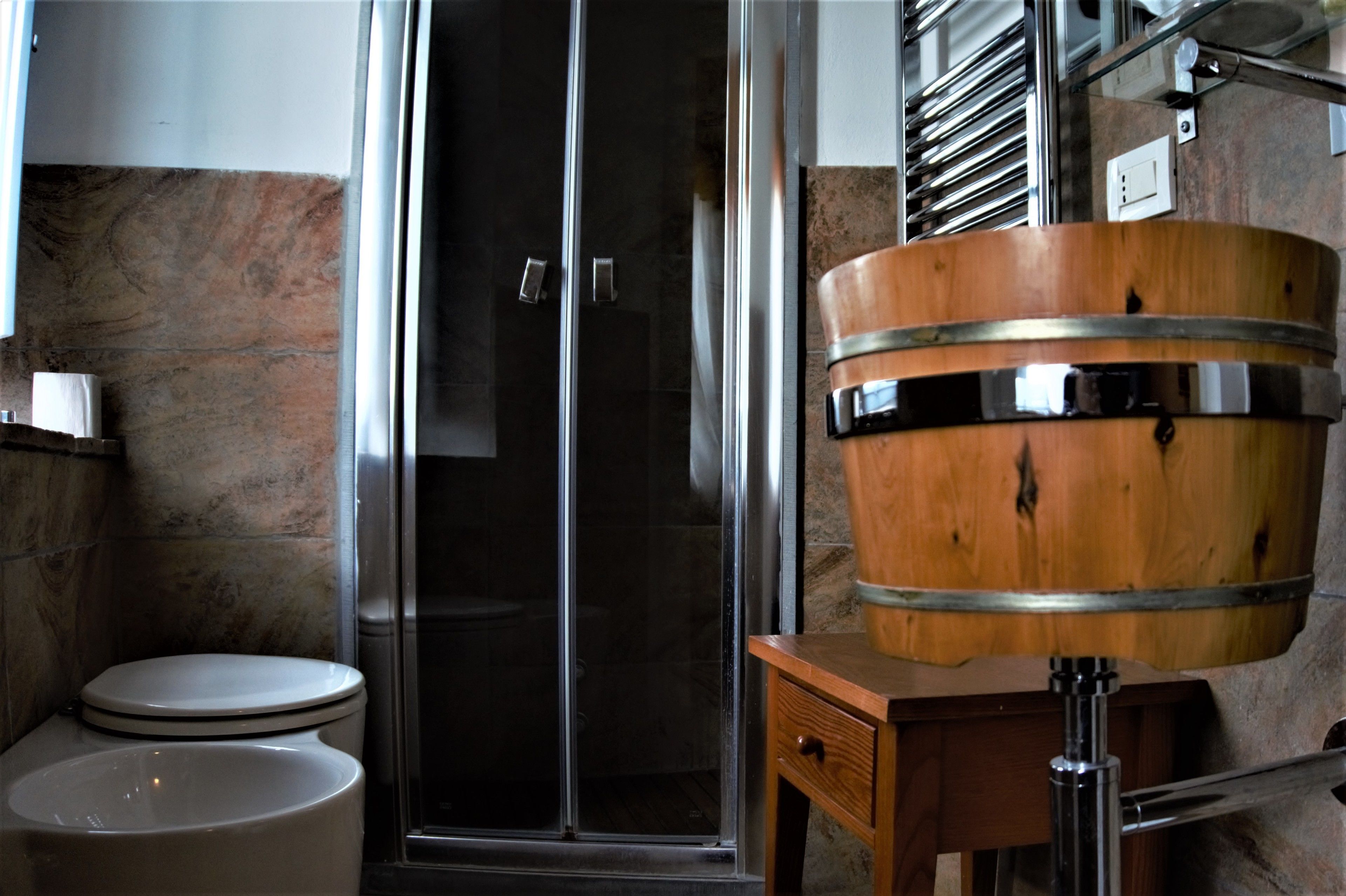 Ein Badezimmer mit Toilette, einer Duschkabine aus Glas und einem Waschbecken aus Holz.