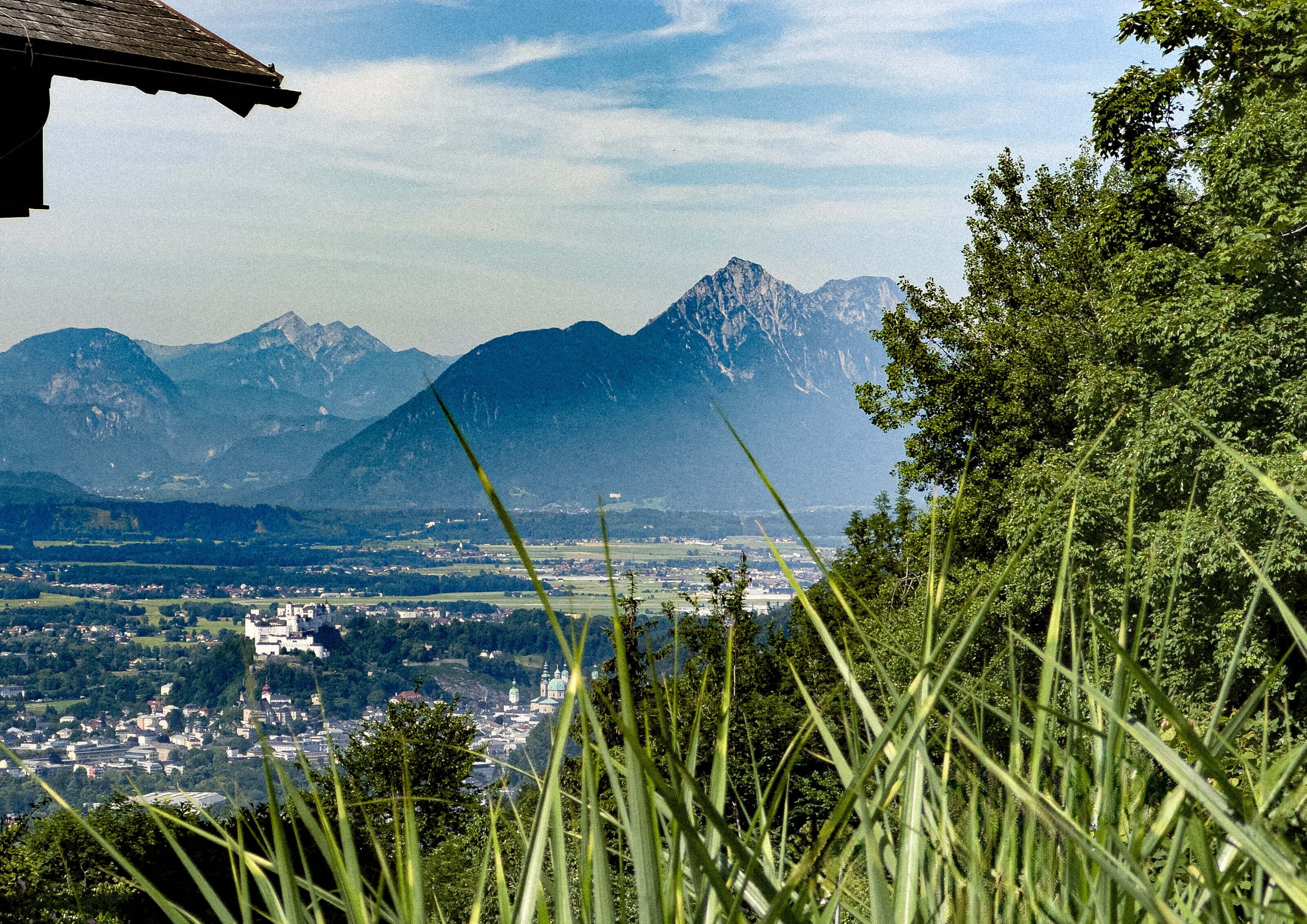 A mountainous landscape with a town in the valley, surrounded by greenery and mountains.