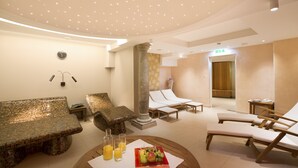 A spa area with a mosaic-tiled bench, lounge chairs, a pillar, and a table with fruit and drinks. - Romantik Hotel die Gersberg Alm mit Panorama über Salzburg und Outdoorpool ab Mai (Salzburg)
