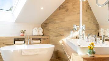 Un baño moderno con una bañera independiente, un tocador con espejo y una pared decorativa de madera.