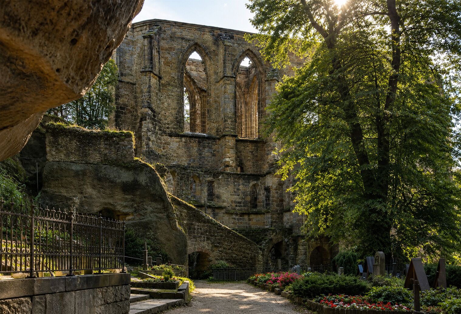 Un edificio antiguo de piedra con ventanas arqueadas y un jardín circundante.