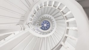 A spiral staircase with white railings and a blue patterned center. - Schlosshotel Althörnitz (Bertsdorf-Hoernitz)