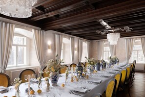 A long dining table set for a formal event, with vases, candles, and a chandelier.