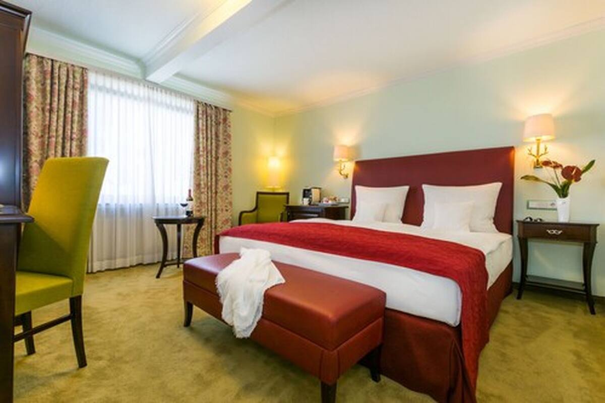 Habitación de hotel con una cama grande, una mesita de noche, una silla y un escritorio.