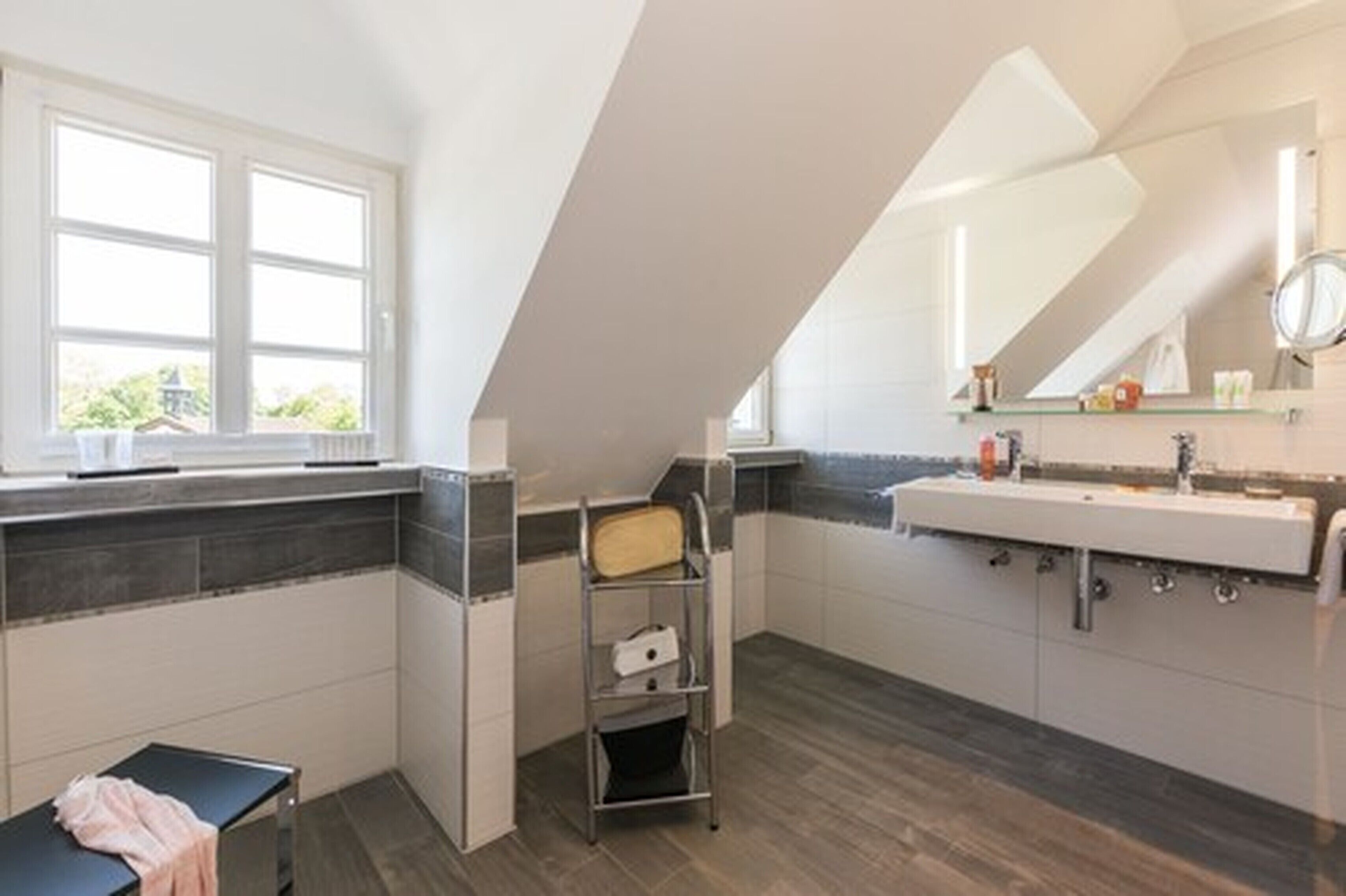 Ein modernes Badezimmer mit Oberlicht, großem Spiegel und integriertem Waschbecken.