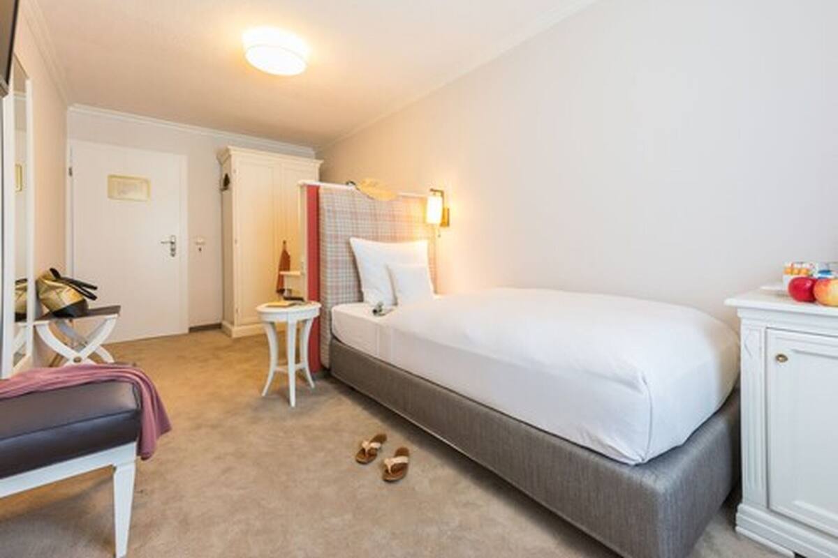 Una habitación de hotel con cama, mesita de noche, silla y armario.