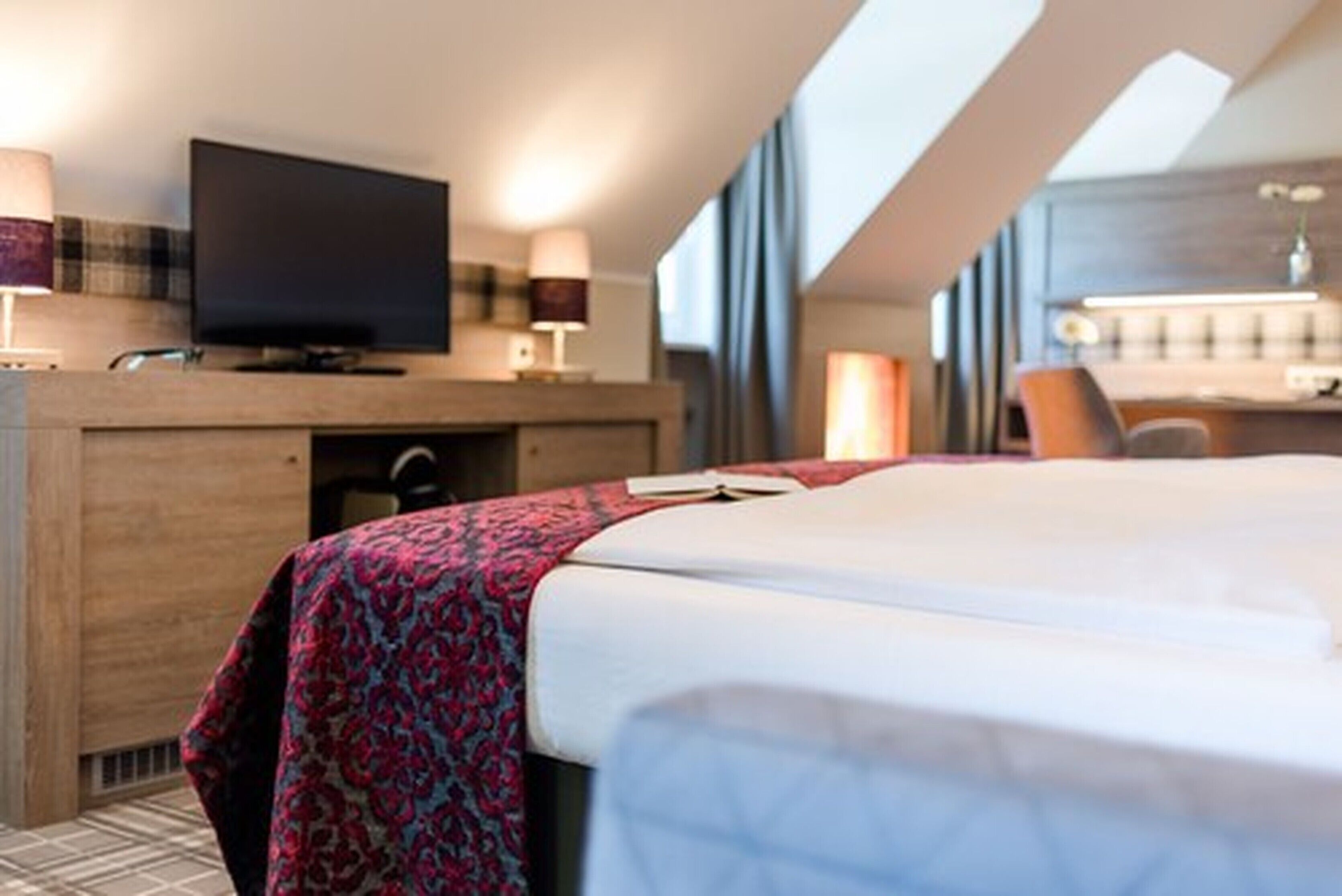 Una habitación de hotel moderna con cama, televisión, escritorio y ventana.
