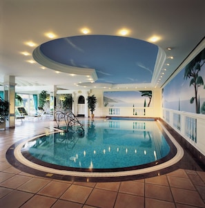 Une grande piscine intérieure dotée d’un plafond incurvé et ornée d’une fresque représentant un paysage.