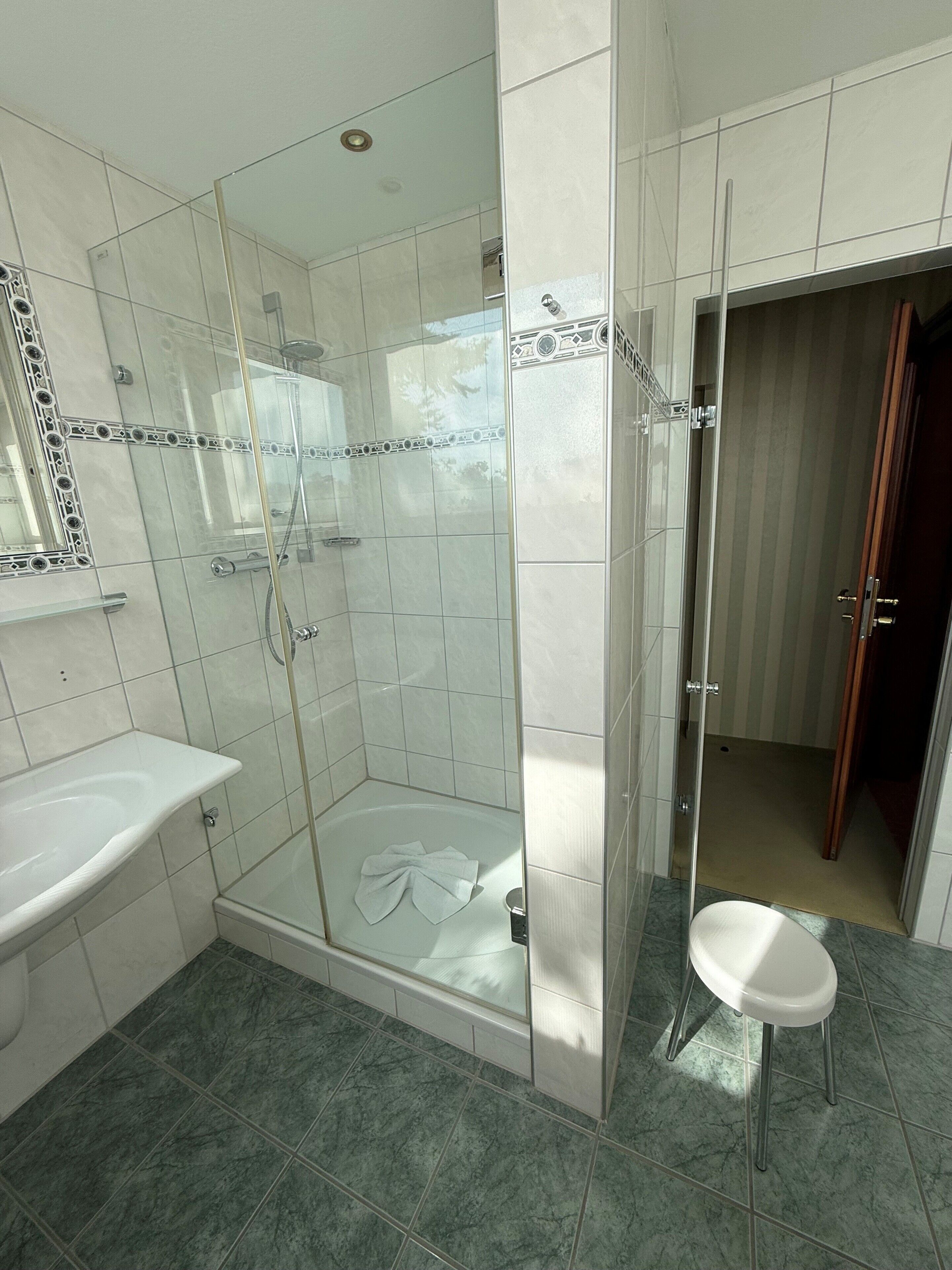 Un baño con ducha de vidrio, lavamanos e inodoro.