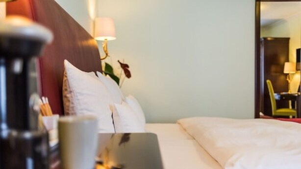 Une chambre d’hôtel comprenant un lit, des oreillers, une table de chevet avec une lampe et une chaise.