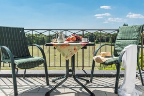 A patio with two green chairs, a small table with a floral tablecloth, and a metal railing. - Lohmann's Romantik Hotel Gravenberg (Langenfeld)