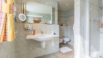 A modern bathroom with a large sink, a mirror, a shower, and a toilet.