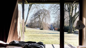 A bedroom with a large window, a bed, and a lamp. - Romantik Hotel Le Val d'Amblève (Stavelot)