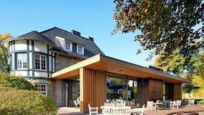 A modern building with a covered outdoor seating area and a stone facade. - Romantik Hotel Le Val d'Amblève (Stavelot)