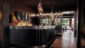 A bar area with a marble countertop, hanging light fixtures, and a wine rack. - Romantik Hotel Le Val d'Amblève (Stavelot)