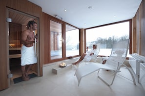 A modern room with a large window, a bench, and a small table with candles. - Romantik Hotel Le Val d'Amblève (Stavelot)