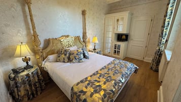 Un dormitorio con una cama grande, un cabecero decorativo, un mueble para televisión y una colcha estampada.
