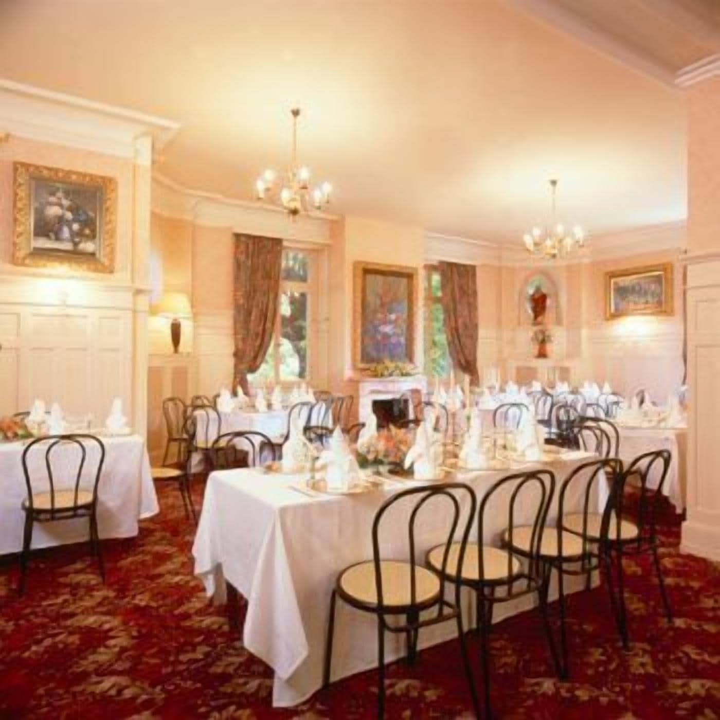 A formal dining room with tables set for service, featuring classic decor and a carpeted floor.
