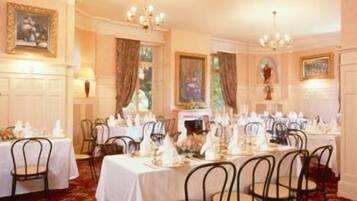 A formal dining room with tables set for service, featuring classic decor and a carpeted floor.